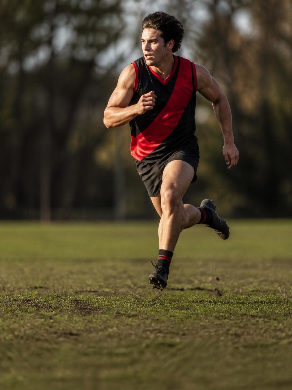 Athlete sprinting in a black and red Divley performance jersey